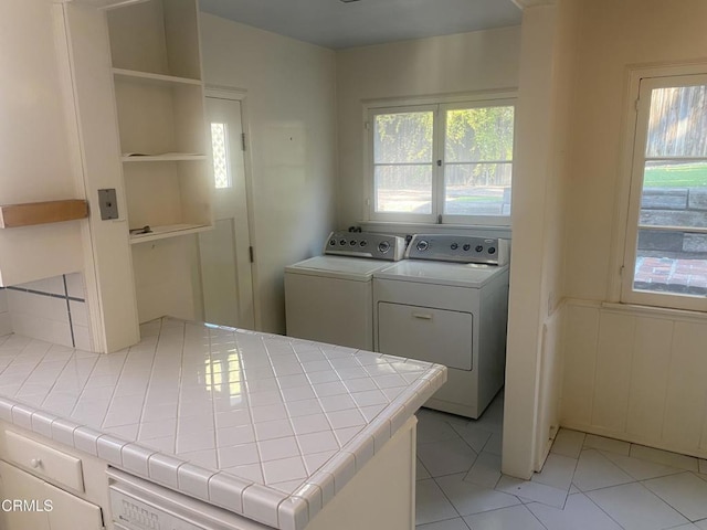 clothes washing area with light tile patterned flooring and washer and clothes dryer