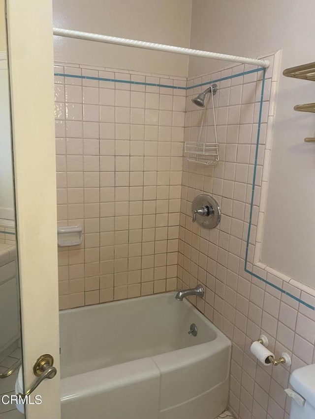 bathroom with tiled shower / bath, tile walls, and toilet