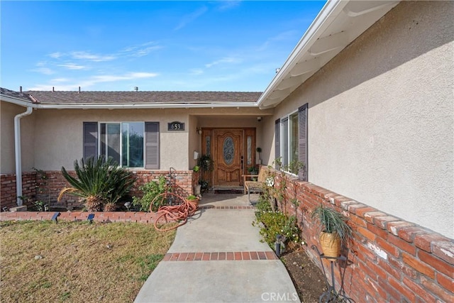 entrance to property featuring brick siding and stucco siding