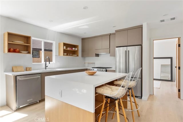 kitchen with sink, a kitchen breakfast bar, a center island, light hardwood / wood-style floors, and stainless steel appliances