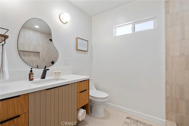 bathroom with vanity, a tile shower, and toilet