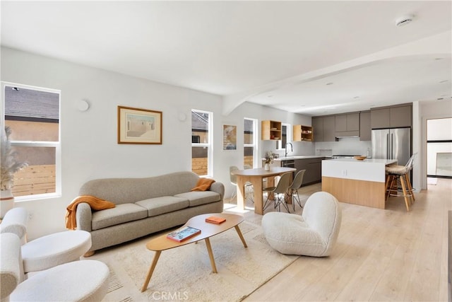 living room with plenty of natural light, sink, and light wood-type flooring