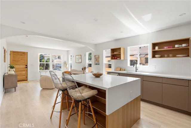 kitchen with sink, a breakfast bar area, light hardwood / wood-style floors, and a center island