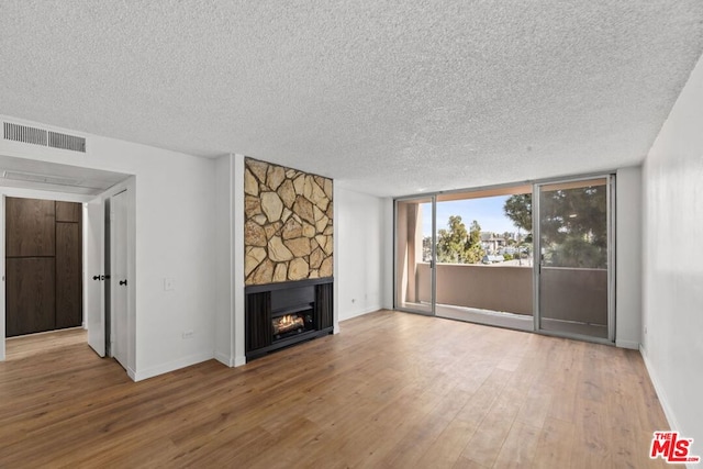 unfurnished living room with wood-type flooring, a textured ceiling, and a fireplace