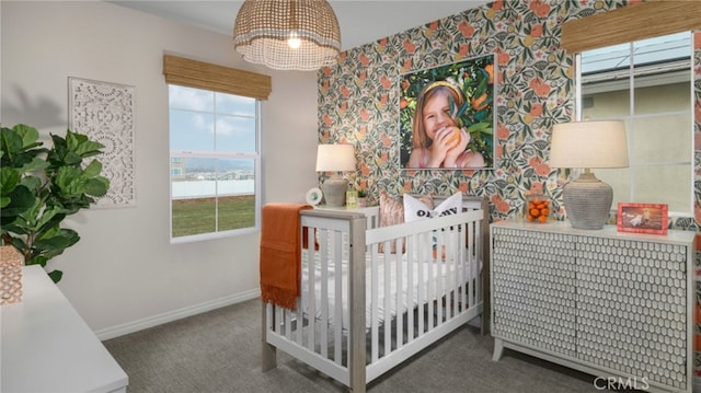 bedroom with a nursery area and dark colored carpet