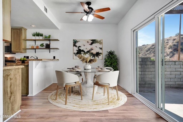 dining area featuring ceiling fan, a mountain view, and light wood-type flooring