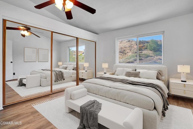 bedroom with lofted ceiling, a closet, ceiling fan, and light wood-type flooring