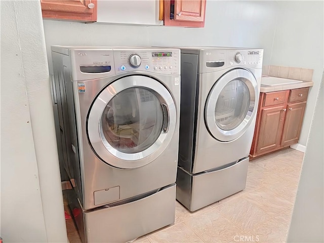 laundry area featuring washer and clothes dryer and cabinets