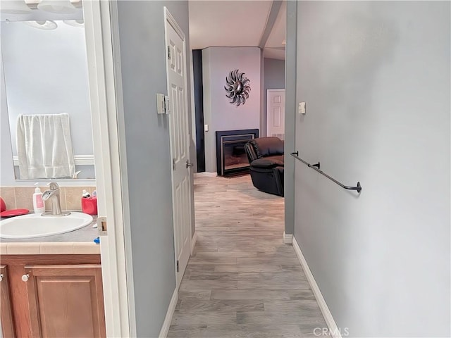 hallway with sink and light hardwood / wood-style flooring