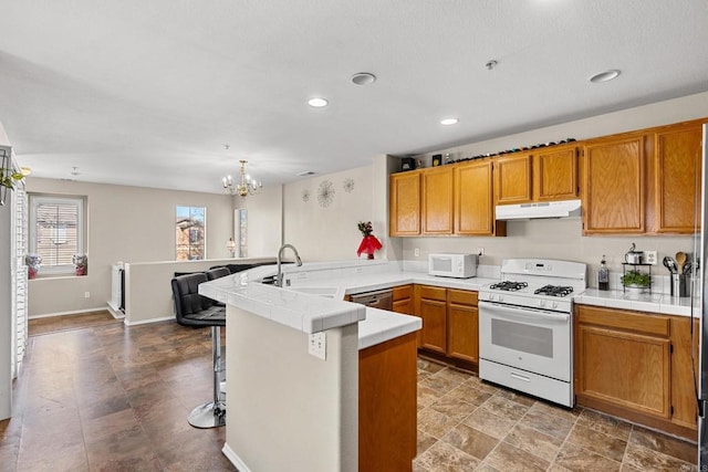 kitchen with sink, a kitchen bar, hanging light fixtures, kitchen peninsula, and white appliances