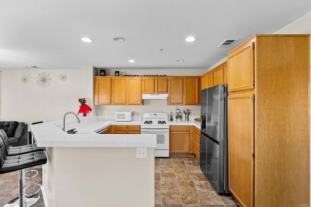 kitchen with white appliances, a kitchen bar, kitchen peninsula, and sink