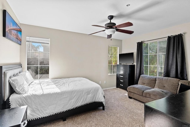 carpeted bedroom featuring multiple windows and ceiling fan