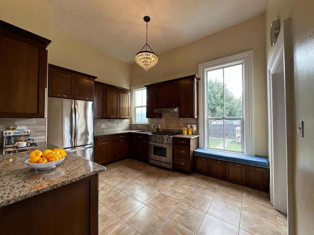 kitchen featuring sink, light stone counters, decorative light fixtures, stainless steel appliances, and decorative backsplash