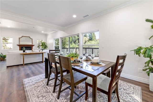 dining room with dark wood-type flooring, ornamental molding, and plenty of natural light