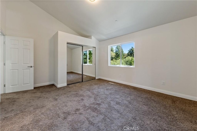 unfurnished bedroom featuring lofted ceiling, a closet, and carpet flooring