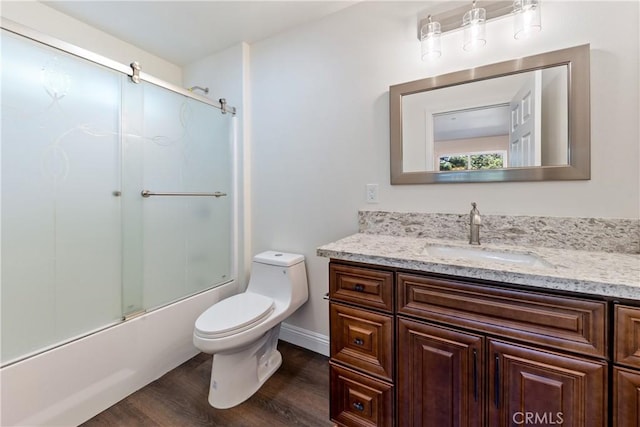 full bathroom with wood-type flooring, combined bath / shower with glass door, vanity, and toilet