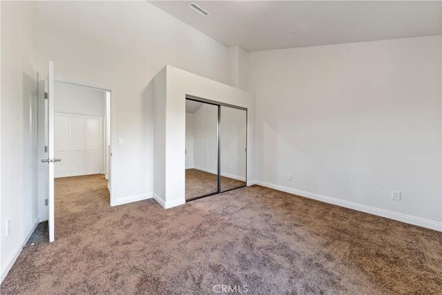 unfurnished bedroom with vaulted ceiling, carpet flooring, and a closet