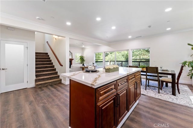 kitchen with crown molding, light stone countertops, a center island, and dark wood-type flooring