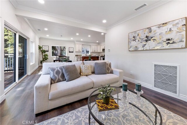 living room with ornamental molding, dark wood-type flooring, and a healthy amount of sunlight