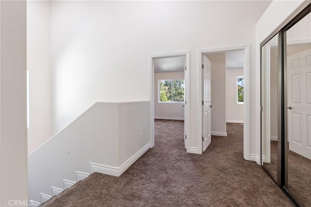 hall featuring dark colored carpet