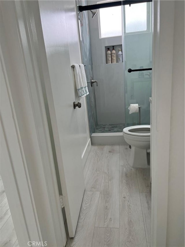 bathroom with walk in shower, toilet, and hardwood / wood-style floors