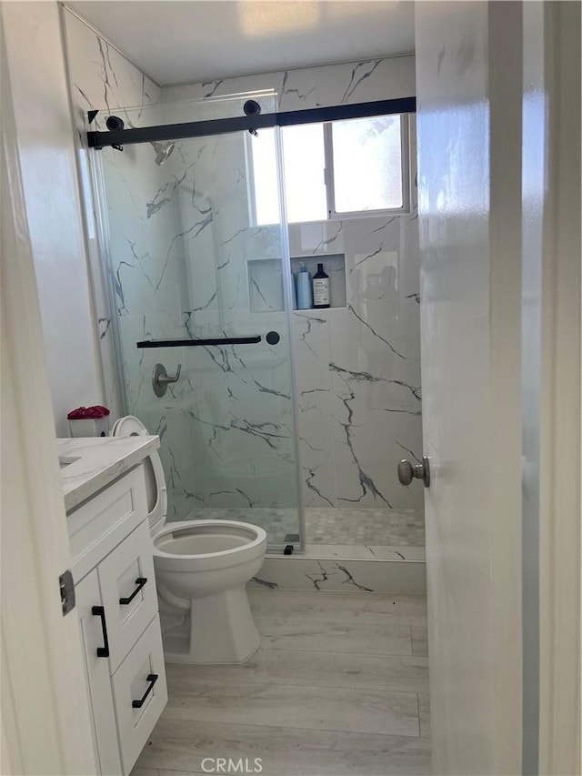 bathroom with walk in shower, vanity, and toilet