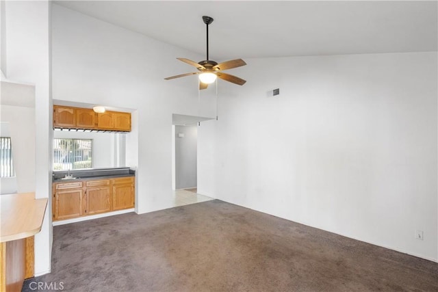 unfurnished living room with dark carpet, high vaulted ceiling, and ceiling fan