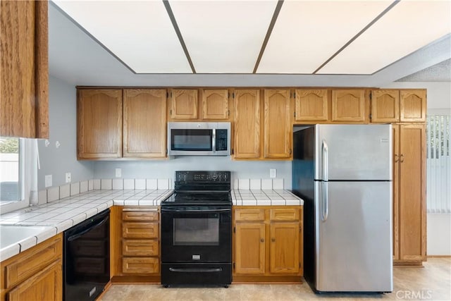 kitchen with tile countertops and black appliances