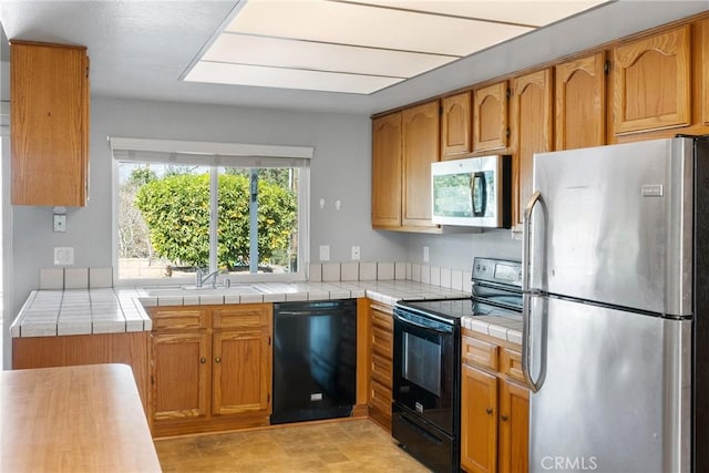 kitchen featuring tile counters, sink, and black appliances