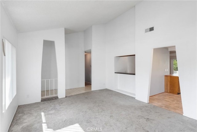 unfurnished living room with light colored carpet and high vaulted ceiling