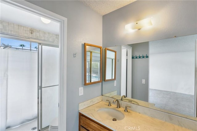 bathroom with vanity, a shower, a textured ceiling, and toilet