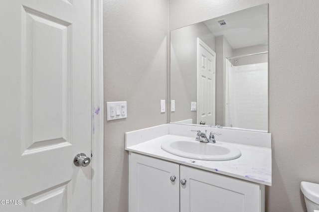 bathroom with vanity, a shower, and toilet