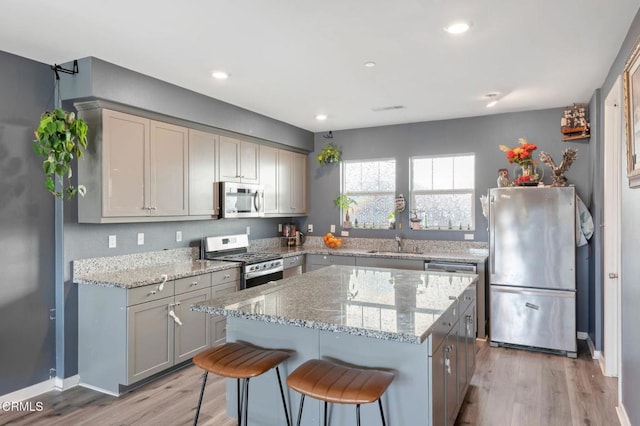 kitchen featuring gray cabinets, a kitchen island, appliances with stainless steel finishes, sink, and light wood-type flooring