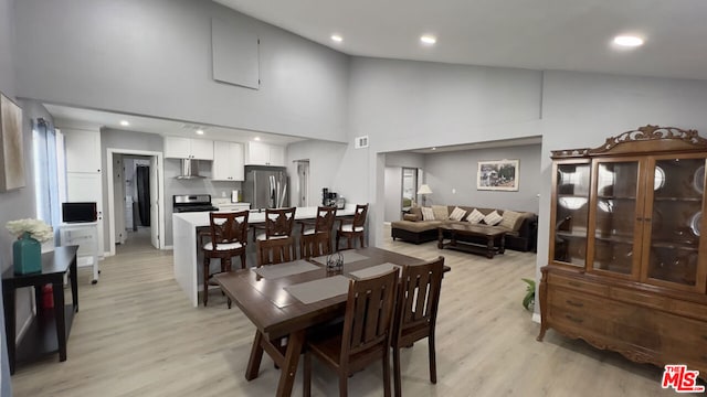 dining room featuring high vaulted ceiling and light hardwood / wood-style floors