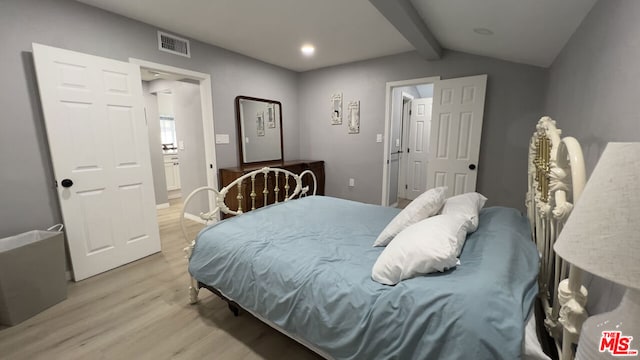 bedroom with lofted ceiling with beams and light wood-type flooring