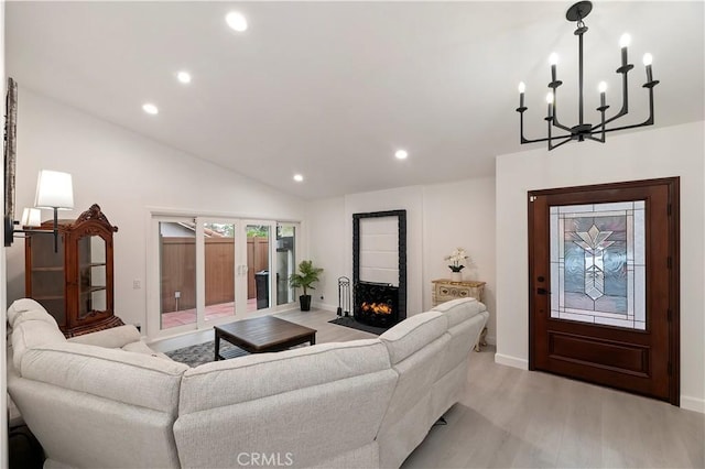 living room with french doors, a notable chandelier, lofted ceiling, and light wood-type flooring