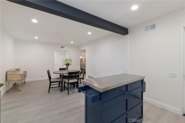 dining room featuring beam ceiling and light wood-type flooring