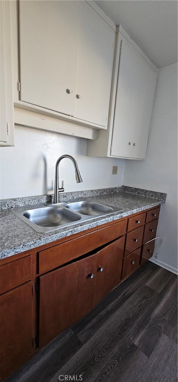 kitchen with dark hardwood / wood-style floors, sink, and white cabinets