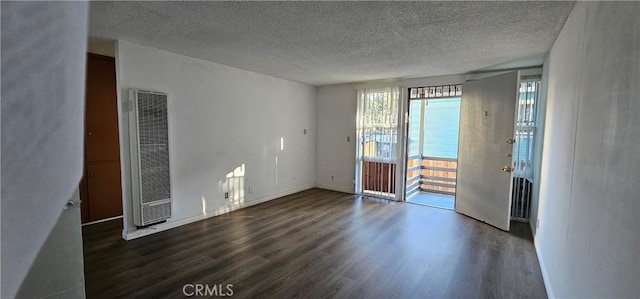 empty room with dark hardwood / wood-style floors and a textured ceiling