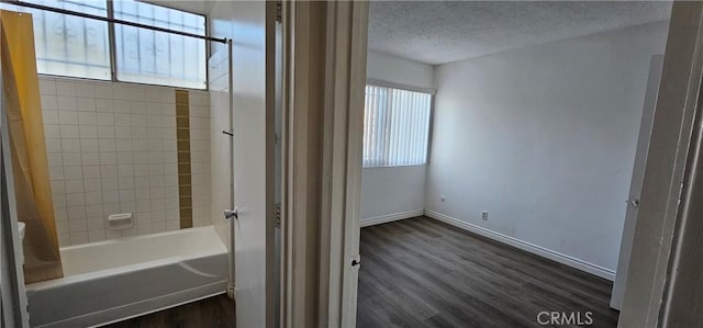 bathroom with tiled shower / bath combo, wood-type flooring, a wealth of natural light, and a textured ceiling