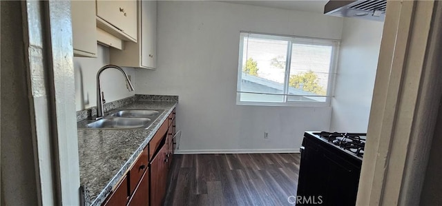 kitchen with black gas range oven, sink, dark wood-type flooring, and dark stone counters