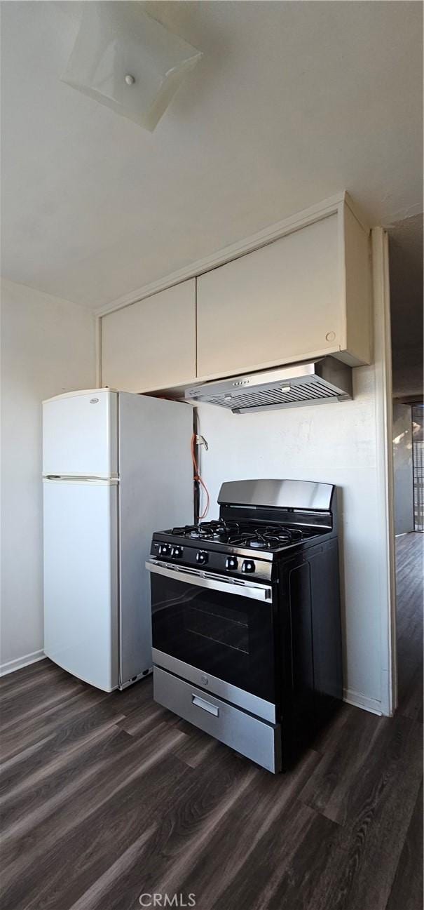 kitchen featuring wall chimney range hood, dark hardwood / wood-style floors, gas stove, and white refrigerator