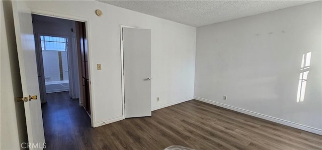 empty room featuring a healthy amount of sunlight, dark hardwood / wood-style floors, and a textured ceiling