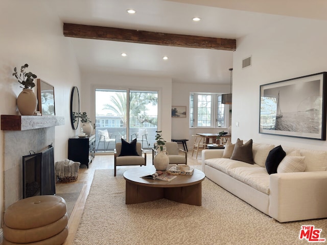 living room featuring beamed ceiling and a tiled fireplace