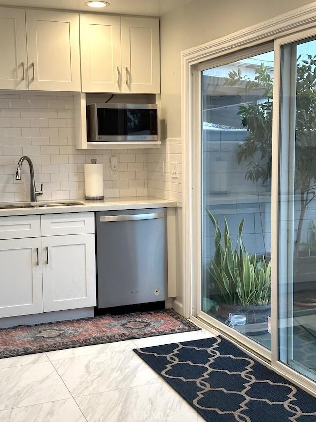 kitchen with sink, backsplash, white cabinets, and appliances with stainless steel finishes