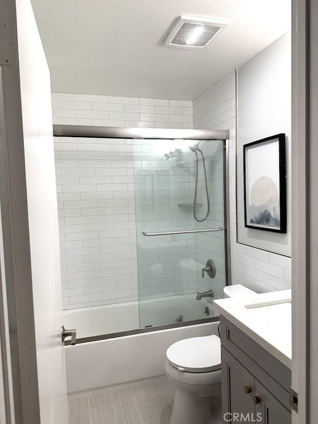 full bathroom featuring vanity, tile patterned flooring, shower / bath combination with glass door, and toilet