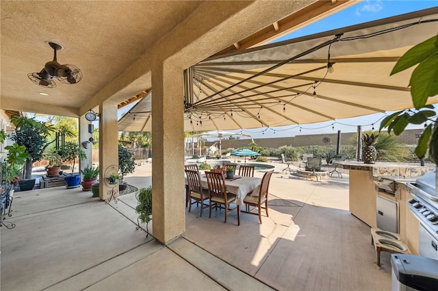 view of patio / terrace with a pool, ceiling fan, and exterior kitchen