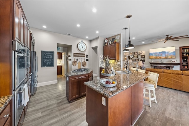 kitchen with decorative light fixtures, a center island, kitchen peninsula, and light wood-type flooring