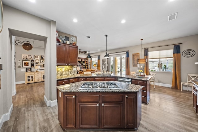 kitchen featuring hanging light fixtures, light hardwood / wood-style flooring, appliances with stainless steel finishes, kitchen peninsula, and a kitchen island