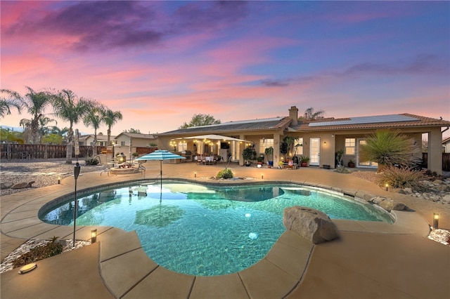 pool at dusk with a patio area